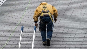 Residential Roof Replacement in Rhode Island | Roofer walking up roof with ladder next to him | Miceli Roofing