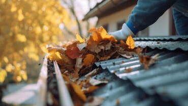 Spring Gutter Cleaning | Person clearing gutters of leaves on house and gutter cleaning | Miceli Roofing